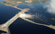 Vista aérea de la presa hidroelectrica evacuando agua rodeada de puestos hidroelectricos encargados de transportar la energía